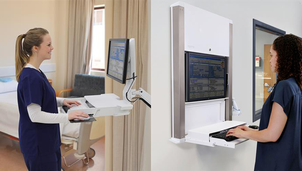 Dua orang pekerja medis sedang bekerja menggunakan wall workstation Ergotron untuk melihat data pasien