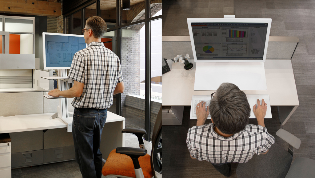 Seorang pegawai kantoran sedang bekerja sambil berdiri dengan nyaman menggunakan standing desk Ergotron.